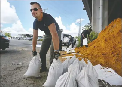  ?? The Associated Press ?? PREPARATIO­NS: Kevin Orth loads sandbags into cars on Milford Street as he helps residents prepare for Hurricane Florence, Monday, in Charleston, S.C.