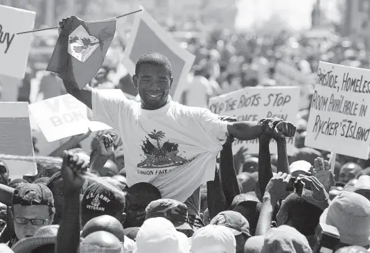  ?? AP PHOTOS ?? Guy Philippe, who led the rebellion against former President Jean-Bertrand Aristide, is greeted by supporters during a march of thousands in Port-auPrince, Haiti, on March 7, 2004. In December 2001, then a police official, Philippe attacked the National Palace in an attempted coup which led Haitian President Jean-Bertrand Aristide to call on the gangsters to rise from the slums.