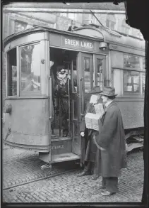  ?? [PHOTO PROVIDED BY LIBRARY OF CONGRESS/AP] ?? BELOW: In this 1918-1919 photo made available by the Library of Congress, a conductor checks to see if potential passengers are wearing masks in Seattle. During the influenza epidemic, masks were required for all passengers.