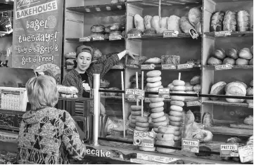  ?? — WP-Bloomberg photos ?? At the baked-goods counter of Zingerman’s Delicatess­en, Fiona Carey, 23, helps a customer make a bread choice.