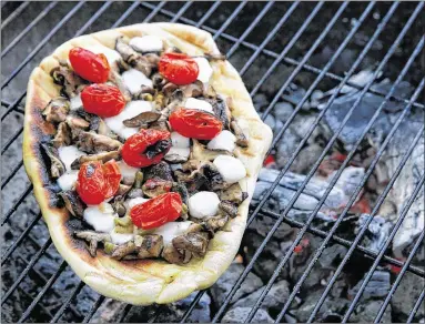  ?? TINA PHAN PHOTOS / AMERICANST­ATESMAN ?? Grilled pizzas, such as this one topped with mushrooms, tomatoes and mozzarella, bubble and blister as if theywere cooked in a wood-fired oven. The key to success with grillbakin­g any kind of dough is getting the grill nice and hot, because every time...