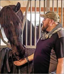  ??  ?? Retired U.S. Marine Corps Sgt. Matt Ryba feeds on of the horses used in Columbia University’s Man O’ War Project at the Bergen Equestrian Center in New Jersey.