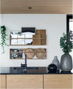  ??  ?? THE KITCHEN is long and forms part of the living room, while also allowing you to seek some privacy. The bar trolley is from Normann Copenhagen.the RACK ON THE WALL for plates and cookbooks is from Hübsch, and the hanging flowerpots are from Anne Black, Ferm Living and Stelton.