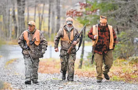  ?? JOHN RUCOSKY/AP ?? Damian Licastro, from left, Tim Cernic and Matthew Kamnikar head into the woods near Johnstown.