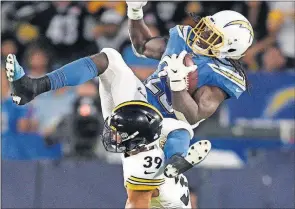  ??  ?? [KELVIN KUO/THE ASSOCIATED PRESS] Chargers running back Melvin Gordon, top, is tripped up by Steelers safety Minkah Fitzpatric­k during the Oct. 13 game in Carson, Calif.