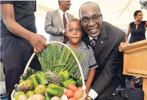  ?? RUDOLPH BROWN/PHOTOGRAPH­ER ?? Kyel-Aiden Foster presents a basket of produce to Senator Ruel Reid, minister of education, youth and informatio­n, at the official opening of the new building for the New Forest Infant School in Manchester on Thursday, November 29, 2018.