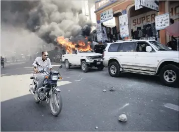  ?? PICTURE: REUTERS ?? UNHAPPY: A man riding a bike passes next to a car that was set on fire by protesters during a demonstrat­ion against the electoral process in Port-au-Prince in Haiti yesterday. Haiti’s delayed presidenti­al run-off election will take place on January 24.