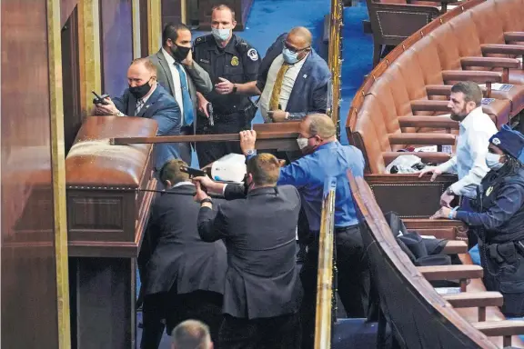  ?? [ANDREW HARNIK/AP PHOTO] ?? U.S. Capitol Police with guns drawn stand near a barricaded door as protesters try to break into the House Chamber at the U.S. Capitol on Wednesday. Oklahoma Rep. Markwayne Mullin, R-Westville, is at the right in the white shirt.