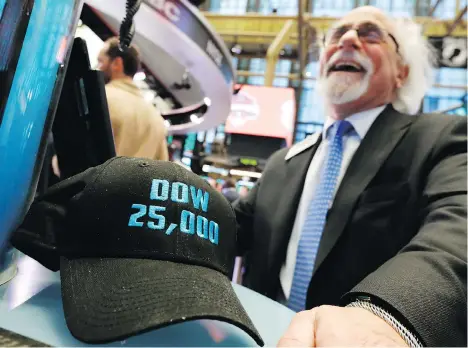  ?? RICHARD DREW/THE ASSOCIATED PRESS ?? A trader poses with a “Dow 25,000” hat on the New York Stock Exchange trading floor last month. The Dow Jones industrial average hit a milestone for the first time by exceeding 25,000 on Jan. 4, quashing fears the decade-long bull market was near death.