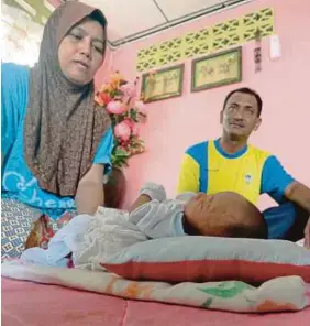  ?? [FOTO EIZAIRI SHAMSUDIN/BH] ?? Mustaqamal dan isteri, Zaleha Kassim, bersama bayi mereka Muhammad Firdaus yang mengalami masalah jantung berlubang, saraf dan masalah buah pinggang, di Kampung Bohor Temak.