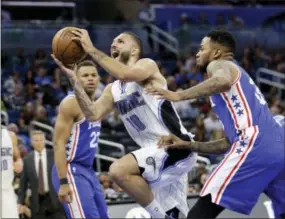 ?? JOHN RAOUX — THE ASSOCIATED PRESS ?? Orlando Magic’s Evan Fournier shoots in between Justin Anderson, left, and Robert Covington of the Sixers in the second half Monday.