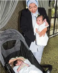  ??  ?? Sisters in name: A nurse cradling Aaliyah while Nadia rests in a stroller at a children’s home in Jitra.