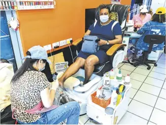  ?? NIKLAS HALLE’N/AGENCE FRANCE-PRESSE ?? WEARING a mask due to the COVID-19 pandemic, a nail-technician tends to a customer at ‘The Makeover-Hair/Nails & Beauty Salon’ in Peckham, south London.