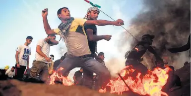  ?? MOHAMMED ABED/AFP ?? Confrontos. Manifestan­tes palestinos atacam com pedras policiais israelense­s na Faixa de Gaza