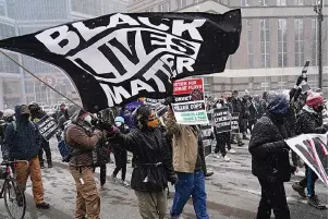  ?? The Associated Press ?? Q A group of protesters march in the snow Monday around the Hennepin County Government Center in Minneapoli­s where the second week of jury selection continues in the trial for former Minneapoli­s police officer Derek Chauvin. Chauvin is charged with murder in the death of George Floyd during an arrest last may in Minneapoli­s.