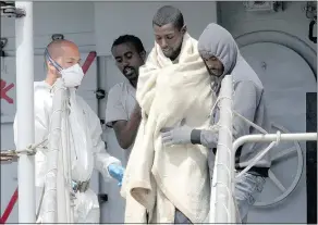  ?? — THE ASSOCIATED PRESS FILES ?? A man is helped disembark from the Italian navy ship Espero as migrants smuggled from North Africa arrive at the Reggio Calabria harbour, southern Italy, Saturday.