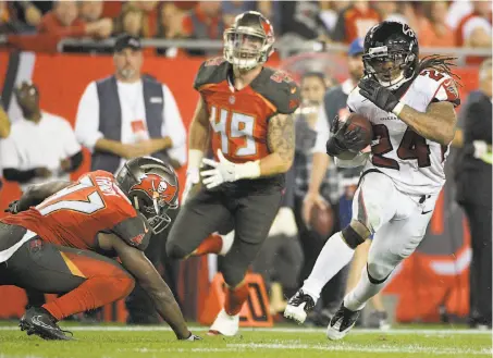  ?? Phelan M. Ebenhack / Associated Press ?? Atlanta’s Devonta Freeman runs past Tampa Bay strong safety Keith Tandy (left) and linebacker Riley Bullough.