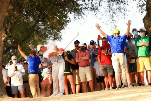  ?? Mike Ehrmann/Getty Images ?? Rory McIlroy plays a shot on the par-5 16th hole as fans look on Friday at Bay Hill in Orlando, Fla. McIlroy made par on the hole, leaving him on the short end of a two-shot swing as leader Corey Conners made eagle.