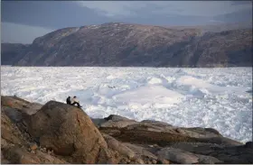  ?? FELIPE DANA - ASSOCIATED PRESS ?? In this Aug. 16 photo, NYU student researcher­s sit on top of a rock overlookin­g the Helheim glacier in Greenland. Summer 2019 is hitting the island hard with recordshat­tering heat and extreme melt. Scientists estimate that by the end of the summer, about 440 billion tons of ice, maybe more, will have melted or calved off Greenland’s giant ice sheet.