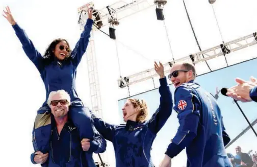  ?? Agence France-presse ?? ↑
Richard Branson, with Sirisha Bandla on his shoulders, exults with crew members on his return from a historic space flight in New Mexico on Sunday.