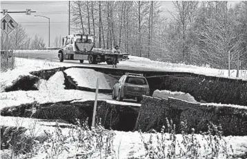  ?? DAN JOLING/AP ?? A tow truck driver assesses a car stuck on a section of an off-ramp that collapsed during an earthquake Friday morning in Anchorage, Alaska. The driver was not injured