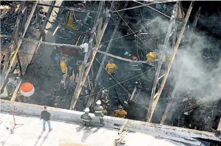  ?? PHOTO: REUTERS ?? Recovery teams examine the charred remains of the two-storey converted warehouse that caught fire killing dozens in Oakland, California.