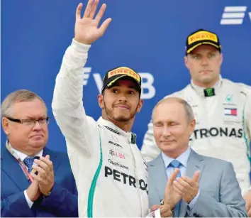  ?? — AFP ?? Winner Mercedes’ British driver Lewis Hamilton celebrates next to and second placed Mercedes’ Finnish driver Valtteri Bottas (R) and Russian President Vladimir Putin during the podium ceremony for the Formula One Russian Grand Prix at the Sochi Autodrom circuit in Sochi.