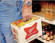  ??  ?? A customer leaves with two cartons of beer at Midwest Wine &amp; Spirits on Monday.