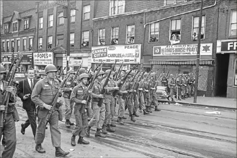  ?? Associated Press ?? Rows of Pennsylvan­ia National Guardsmen march down the street and sidewalks, clearing the area in Pittsburgh’s Hill District on April 8, 1968. Residents lean from windows watching the show of force. The Guardsmen were called out to restore order following three days of arson and looting after the assassinat­ion of Martin Luther King Jr.