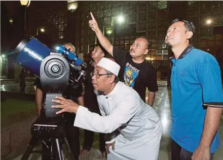 ?? PIC BY AHMAD IRHAM MOHD NOOR ?? Masjid Putra Grand Imam Datuk Abd Manaf (third from right) looking at the ‘blood moon’ and Mars through a telescope in Kuala Lumpur on Friday night.