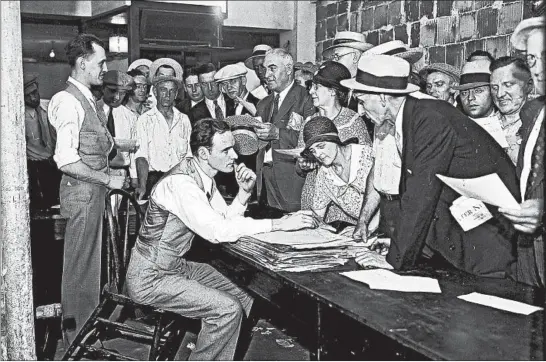  ?? CHICAGO HERALD AND EXAMINER ?? Employees of the Chicago Board of Education apply for payment of their salaries in scrip, a paper IOU, in 1931. Janitors, engineers, teachers, clerks and building contractor­s clamored for a chance to fill out their applicatio­ns for the paper. For many months, the board couldn’t pay its teachers and other employees during the Great Depression.