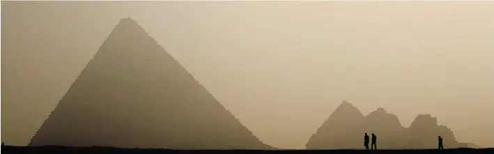  ?? PATRICK BAZ/AFP- Gett y Imag es ?? Egyptian police officers walk a lonely path past pyramids on the outskirts of Cairo, which before the Arab Spring revolution of 2011 would attract droves of tourists.