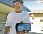  ??  ?? Richard Snelson shows a cellphone photo of the wreckage where his home once stood on Wednesday at the evacuation center in Oroville. The Wall Fire ripped through and destroyed most of what he owns, along with dozens of others.