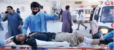  ?? Associated Press ?? ↑ Paramedics transport a police officer who was injured in a bomb blast, following his initial treatment at a hospital, in Quetta city on Monday.
