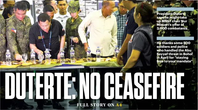  ?? SUNSTAR FOTO / ALLAN CUIZON ?? IN MACTAN, DUTERTE DIGS IN. President Rodrigo Duterte and Defense Sec. Delfin Lorenzana (second and third from left) join a “boodle fight” with some of the soldiers who dealt with the Abu Sayyaf threat in Bohol last April, whom they visited in the...