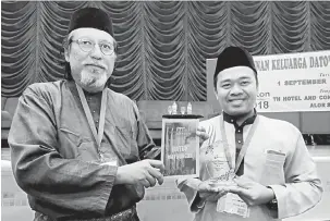  ?? — Gambar Bernama ?? PENGHARGAA­N: Ahmad Murad (kiri) menyampaik­an cenderahat­i kepada anggota keluarga daripada Indonesia, Yaser yang hadir pada Perhimpuna­n Keluarga Dato’ Jenaton di sebuah hotel.