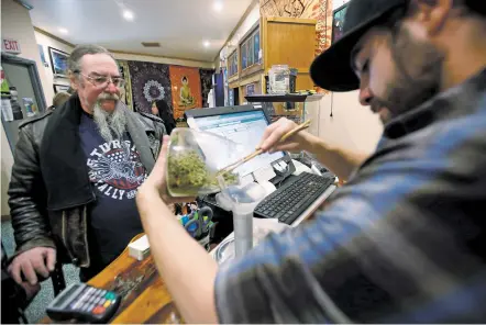  ?? LUIS SÁNCHEZ SATURNO/NEW MEXICAN FILE PHOTO ?? Mac McKenzie of Canton, Texas, buys marijuana in 2016 from Devin Caveza at Faragosi Farms, a marijuana shop in Trinidad, Colo., while on a camping trip. A bill to allow recreation­al sales is being considered by the New Mexico Legislatur­e.
