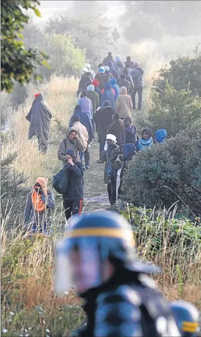  ?? PASCAL ROSSIGNOL / REUTERS ?? Antidistur­bios franceses hacen retroceder a grupos de migrantes en Coquelles, cerca de Calais