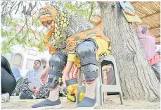  ?? ?? Parveen Bibi (right) adjusts her protective gear before riding a motorbike during a riding lesson with the women-only group ‘Rowdy Riders’.