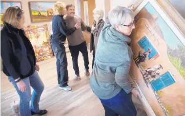  ?? MARLA BROSE/JOURNAL ?? Marigail Littlefiel­d, right, hangs a painting as Mary Ann Weems, second from left and Beth Chavez, fourth from left, thank artist Andrew Rodriguez, third from left, after Rodriguez finished hanging his bas relief sculpture of a woman in prayer inside of Casa Corazon.