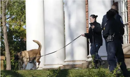  ?? Photograph: Steve Helber/AP ?? A police canine team searches the scene Monday near where a shooting occurred at the University of Virginia in Charlottes­ville.