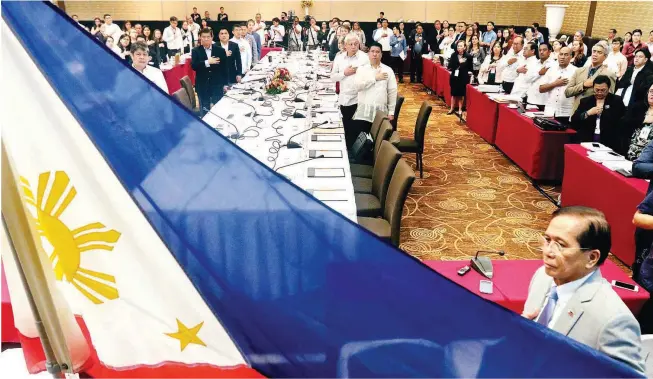  ?? (Mark Balmores) ?? BICAM ON BBL – Secretary Jesus Dureza, presidenti­al adviser on the peace process, holds the flag as senators and congressme­n belonging to the bicameral conference committee sing the national anthem at the start of the bicameral conference for the...