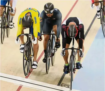  ??  ?? Sandwiched: Malaysia’s Azizulhasn­i Awang (centre) in action during the men’s keirin final at the Jakarta Internatio­nal Velodrome yesterday. He settled for the bronze medal.