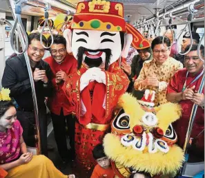  ??  ?? Time for cheer: Hazlan (right) with Ang (second right) spreading festive joy during the Chinese New Year celebratio­n at the Masjid Jamek LRT station.