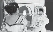  ?? ALTAF QADRI THE ASSOCIATED PRESS ?? A woman takes a photo of her son as he poses in a cutout of an astronaut at the Nehru Planetariu­m in New Delhi, as India’s lunar ambitions soar.