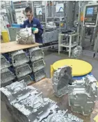  ?? MARK HOFFMAN / MILWAUKEE JOURNAL SENTINEL ?? Production worker Kyle Zahorik loads a transmissi­on case for a Ford pickup truck into a CNC machine at Nemak.