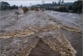  ?? AP PHOTO BY DAMIAN DOVARGANES ?? The Los Angeles River flows downstream in Los Angeles, Jan. 14, 2023. In Los Angeles, a complex system of dams and paved flood control channels including the river were designed to steer water away from roads and buildings and out to sea as fast as possible. But with water sources becoming scarce, efforts are underway to begin capturing and treating some of the runoff for irrigation or to inject in aquifers.