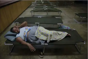  ?? CARLOS GIUSTI — THE ASSOCIATED PRESS ?? Luz Aponte Velazquez lies on a cot at the Ramon Quinones Medina High School, one of the shelters enabled by the municipali­ty of Yabucoa, before the arrival of Tropical Storm Karen, in Yabucoa, Puerto Rico, Tuesday.