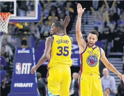  ??  ?? The Warriors’ Kevin Durant is congratula­ted by Stephen Curry after scoring against the Timberwolv­es.