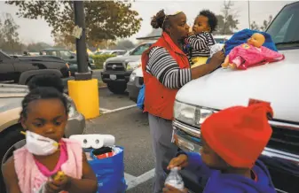  ?? Gabrielle Lurie / The Chronicle ?? Dottie Flanders holds 9-month old grandson Isaiah Brooks and watches over grandchild­ren London, 4 (left), and Messiha Mayo, 3, at a makeshift evacuation center at a Chico Walmart.